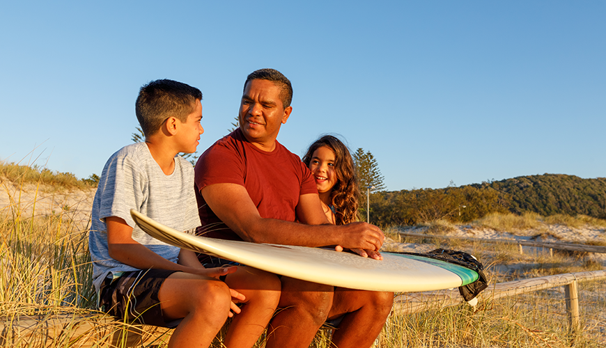 Aboriginal father talking to his children at the beach