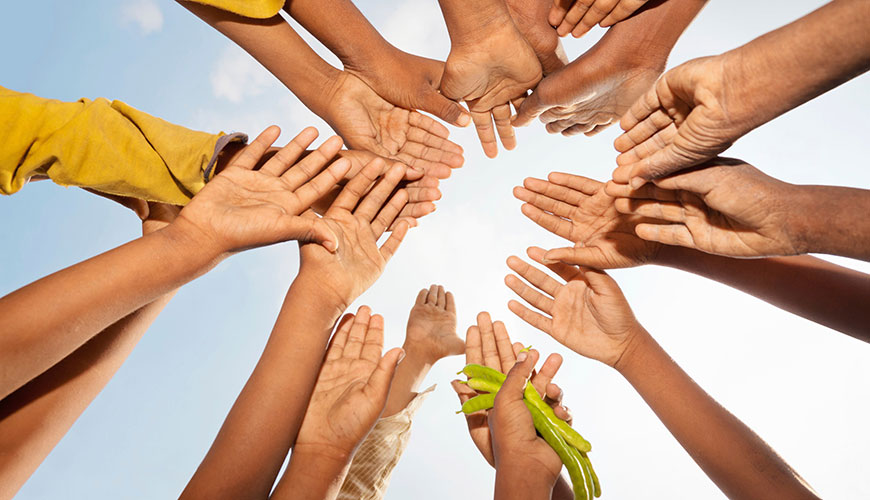 children hands in a circle. One holds beans