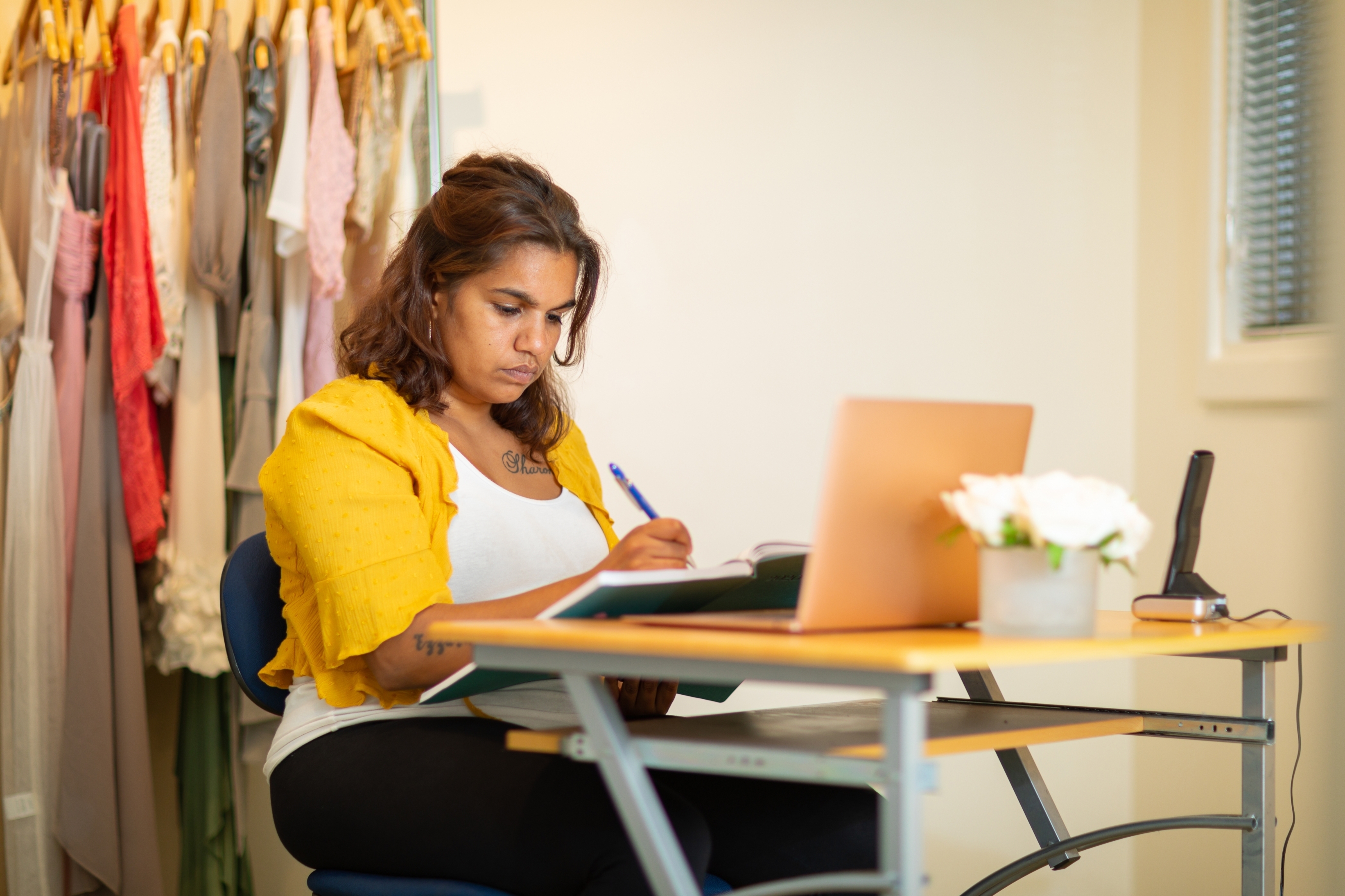 Young person sitting at small desk with laptop and diary