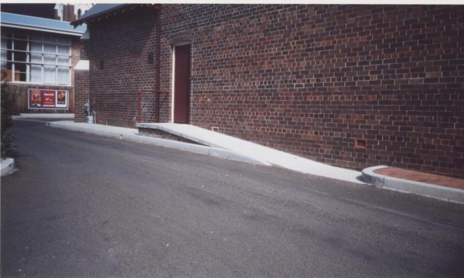 Non-compliant ramp in school setting: no handrails, safety edges or TGSI and landing is too small