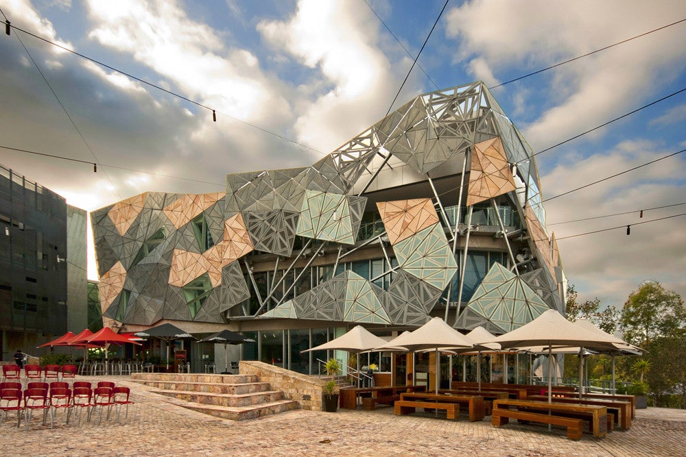 Federation Square in the background, accessible space with a wheelchair ramp, chairs, tables and umbrellas in the foreground