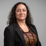 Woman with dark brown long hair wearing top with Indigenous design