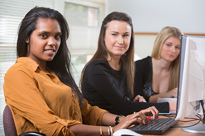 Three office workers sitting around a computer