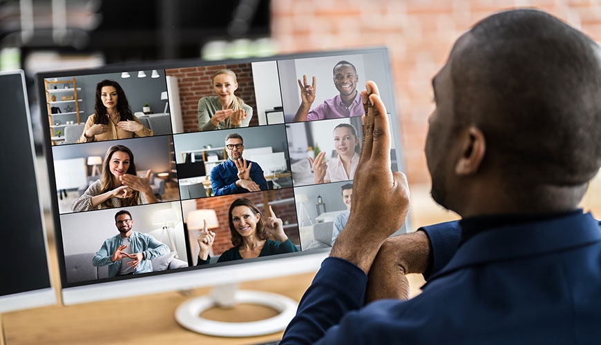 A man of colour participating in a zoom meeting. He is signing to the other 9 participants.