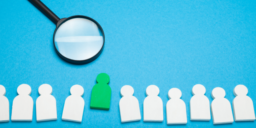 magnifying glass hovering over stand out candidate in a line of figures