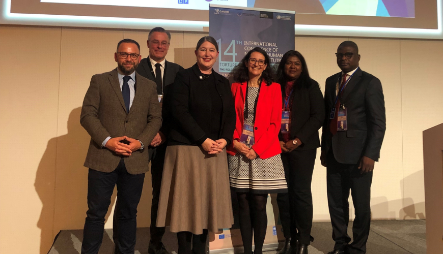 Six people, including Human Rights Commissioner Lorraine Finlay, standing in a conference room in front of a projector screen.