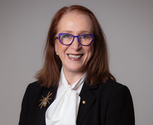 Woman with red hair and glasses smiling