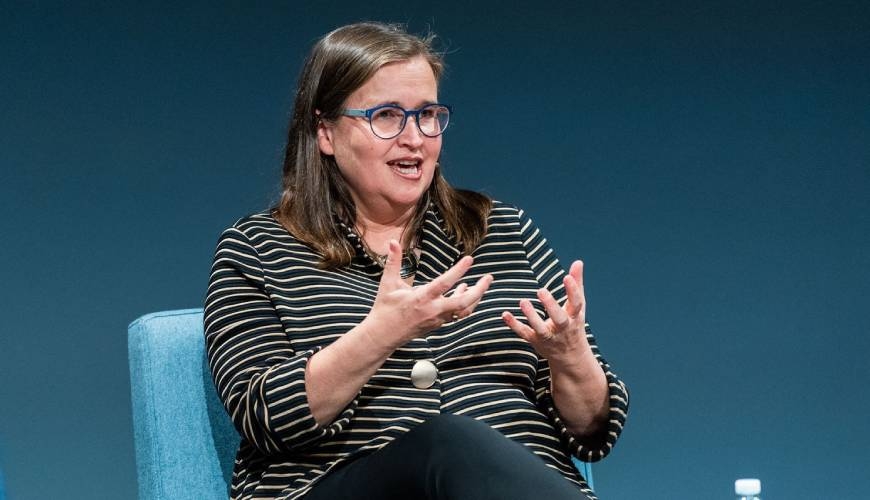 Kate Jenkins on stage speaking, gesturing with her hands.