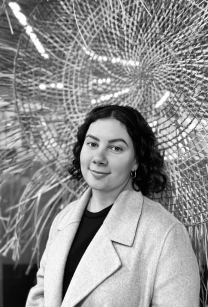 Black and white picture of woman with mid length dark hair wearing a white jacket