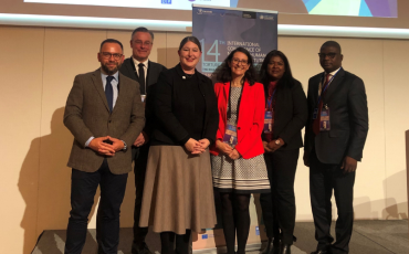 Six people, including Human Rights Commissioner Lorraine Finlay, standing in a conference room in front of a projector screen.