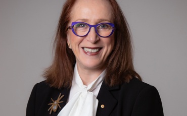 Woman with red hair and glasses smiling