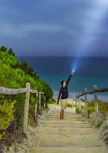 man shining torch at the beach