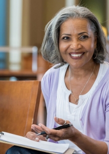 A senior lady at work in a meeting with 2 other females.