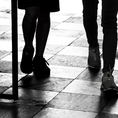 silhouette of two people walking through a barred gate