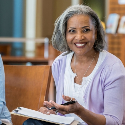 A senior lady at work in a meeting with 2 other females.