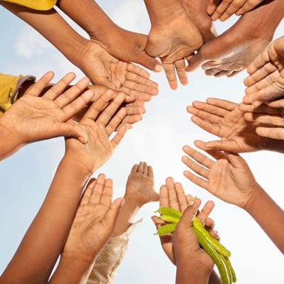 children hands in a circle. One holds beans