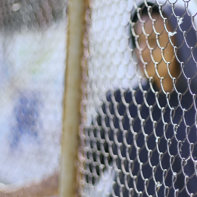 Boy wearing hoodie behind a wire fence