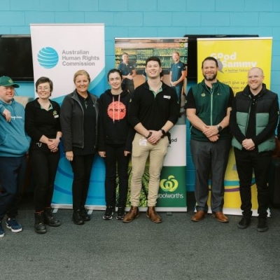 Image of a group of people standing in front of banners from the Australian Human Rights Commission, Good Sammy and Woolworths. 