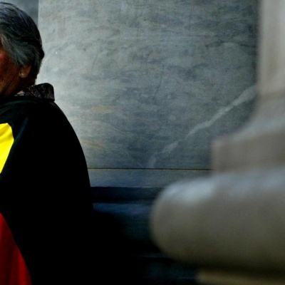 Side profile image of Dr Lowitja O'Dongohue wrapped in the Aboriginal Flag