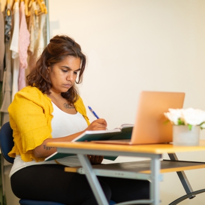 Young person sitting at small desk with laptop and diary